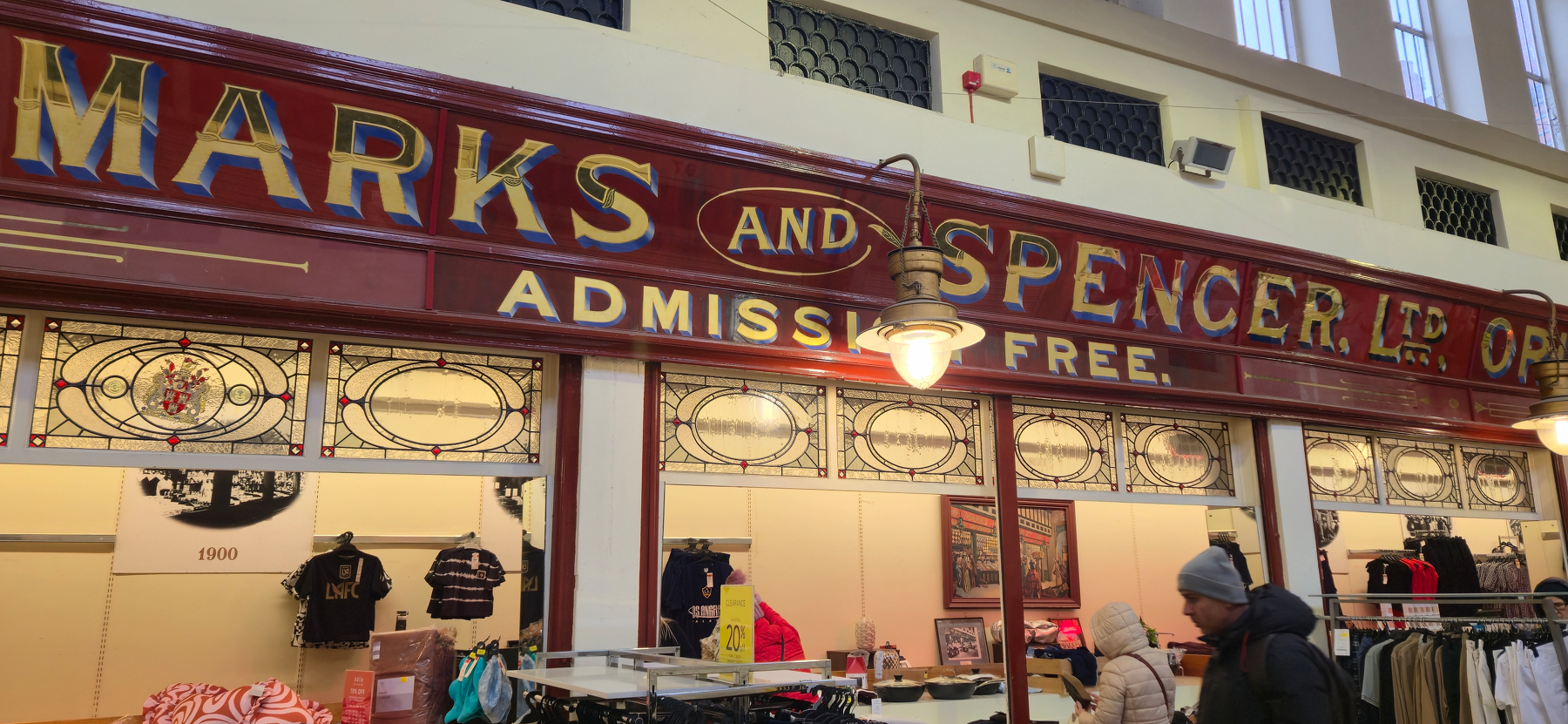 Colorful bird decorations with feather tails are hanging alongside eggs and pom-poms in a craft store.